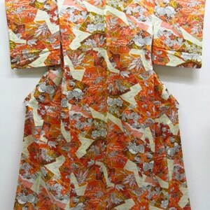 Puede incluir: Un kimono japon&eacute;s tradicional con un patr&oacute;n geom&eacute;trico colorido en tonos naranja, marr&oacute;n y blanco. El kimono est&aacute; hecho de seda y tiene una sensaci&oacute;n de lujo.