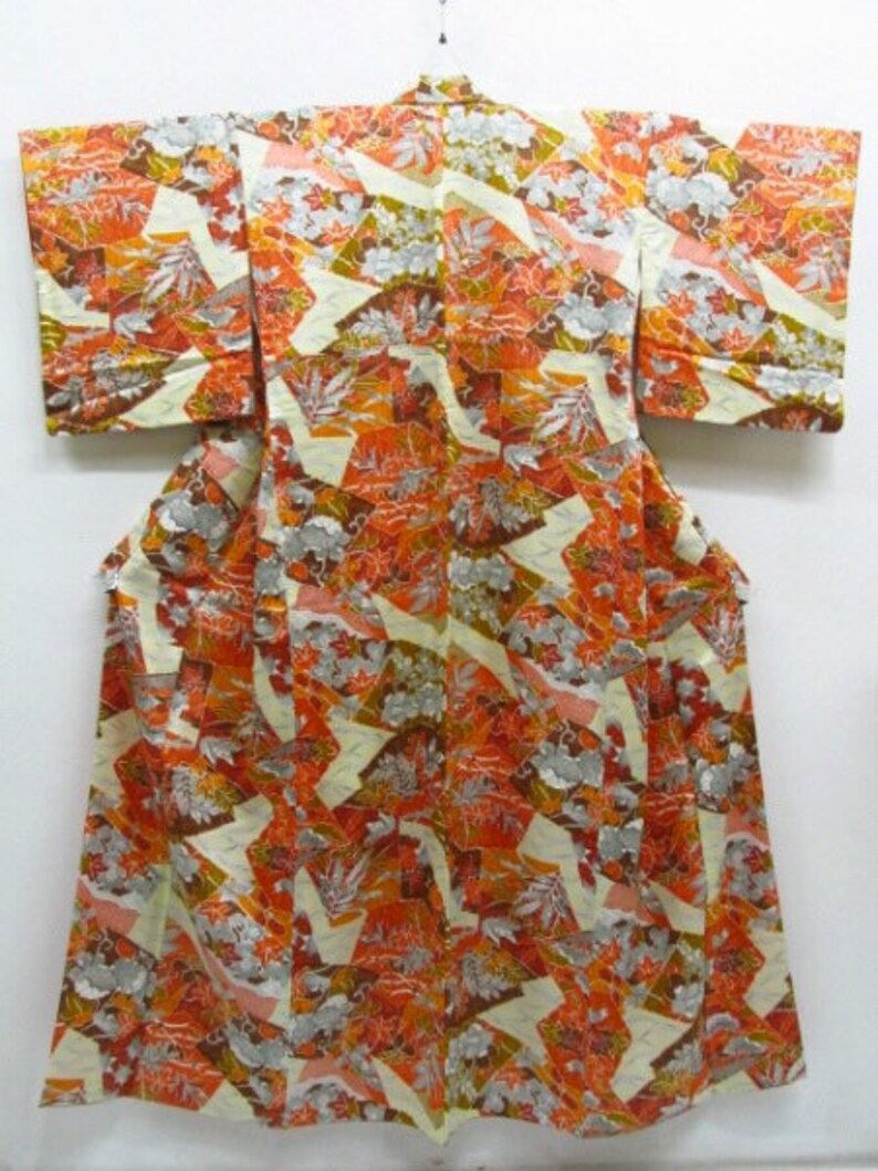 Puede incluir: Un kimono japon&eacute;s tradicional con un patr&oacute;n geom&eacute;trico colorido en tonos naranja, marr&oacute;n y blanco. El kimono est&aacute; hecho de seda y tiene una sensaci&oacute;n de lujo.