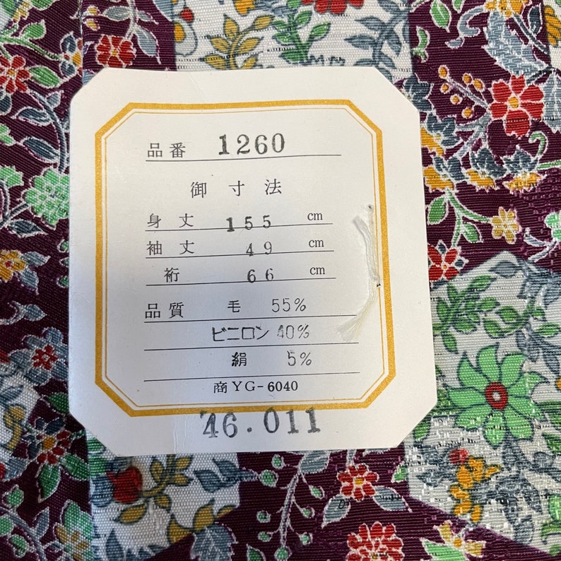 May include: A white tag with black text listing the product number 1260, measurements in centimeters, and fabric composition. The tag is on a purple and white floral fabric.