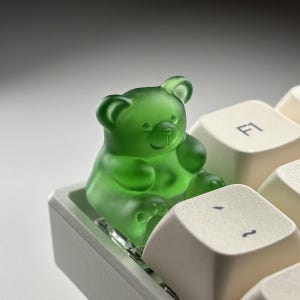 May include: A set of three ceramic mugs with a speckled, matte finish. The mugs are in shades of cream, light gray, and dark gray. Each mug has a simple, minimalist design and a rounded handle.