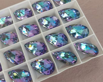 Puede incluir: Vista cercana de una bandeja blanca llena de piedras de cristal en forma de lágrima iridiscentes de color púrpura y azul.