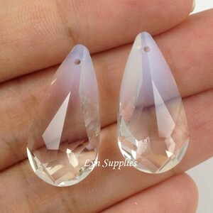 May include: Two clear glass teardrop-shaped crystal pendants with a hole at the top for hanging. The crystals have a faceted design and a slight iridescent shimmer.