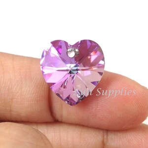 May include: A purple heart-shaped crystal pendant with a hole for stringing. The crystal is faceted and has a light purple hue.