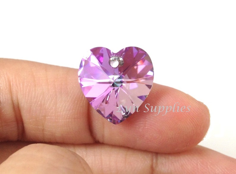 May include: A purple heart-shaped crystal pendant with a hole for stringing. The crystal is faceted and has a light purple hue.