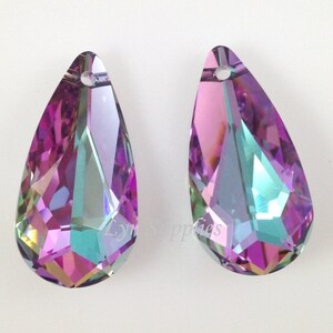 May include: Two iridescent teardrop-shaped crystal pendants with a hole at the top for hanging. The crystals are a mix of purple, pink, and green.