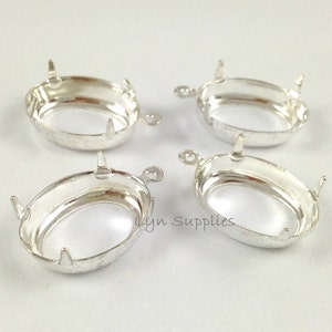 May include: Four silver oval-shaped pendant settings with prongs. The settings are designed to hold a cabochon stone.