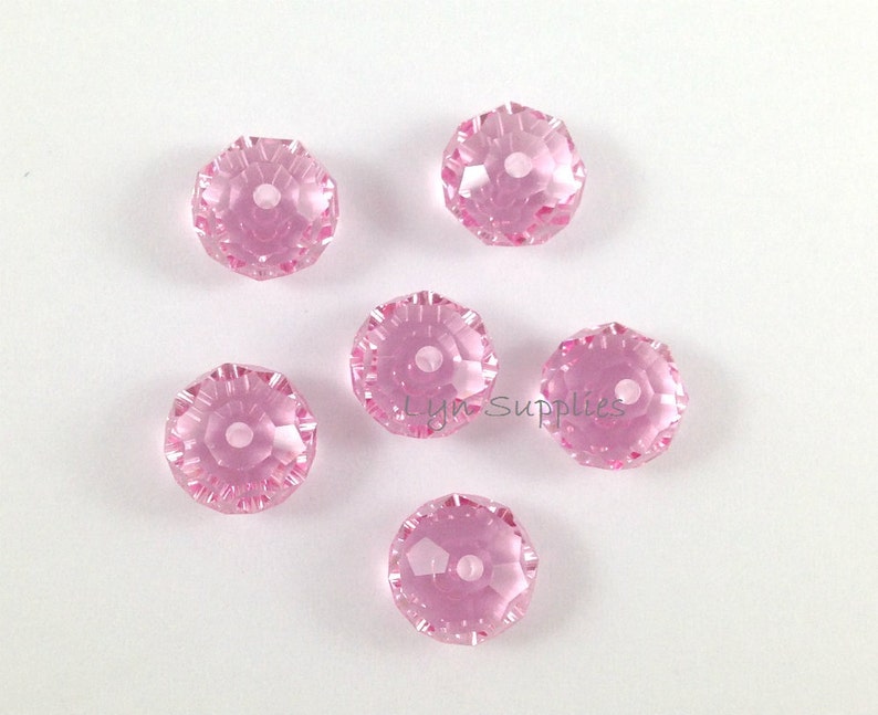 May include: Six pink faceted crystal beads with a hole in the center. The beads are approximately 10mm in diameter.