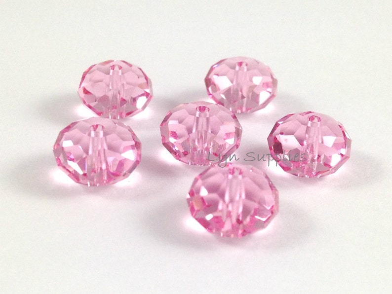 May include: Six pink crystal beads with a hole through the center. The beads are faceted and have a shiny finish.