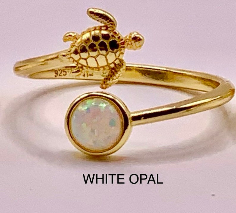 May include: Gold ring with a white opal stone and a small turtle design. The ring is marked "925" on the band.  WHITE OPAL.