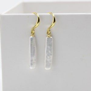 May include: A pair of gold dangle earrings with white baroque pearl drops.