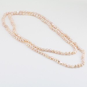 May include: A long, delicate necklace made of pale pink freshwater pearls. The pearls are strung on a thin silver chain and are arranged in a simple, elegant design.