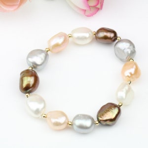 May include: A bracelet made of natural freshwater pearls in shades of white, pink, and brown. The pearls are strung on a gold chain.