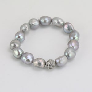 May include: A silver pearl bracelet with a silver and clear crystal bead in the center.