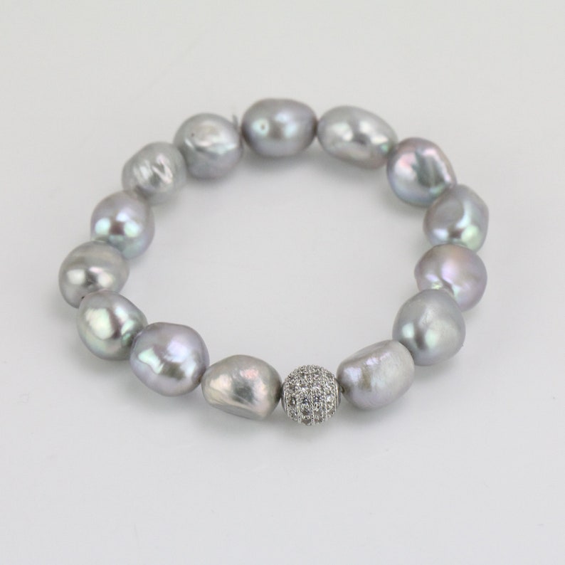May include: A silver pearl bracelet with a silver and clear crystal bead in the center.