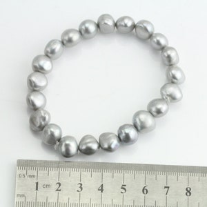 May include: A silver pearl bracelet with a diameter of approximately 6.5 cm. The bracelet is made of 16 round, irregular pearls.