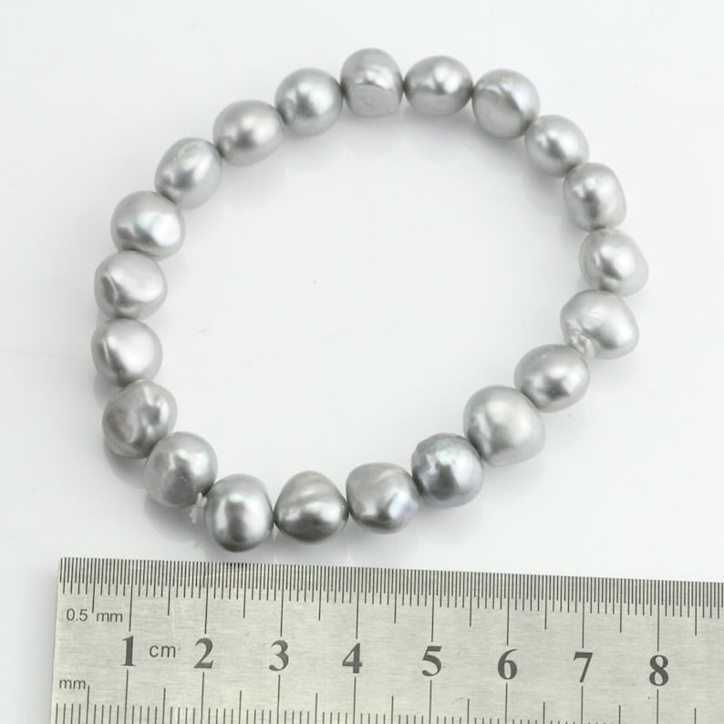 May include: A silver pearl bracelet with a diameter of approximately 6.5 cm. The bracelet is made of 16 round, irregular pearls.