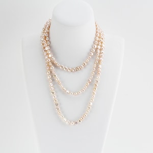 May include: A long, multi-strand necklace made of off-white pearls. The pearls are slightly irregular in shape and have a subtle sheen.