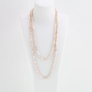 May include: A long, layered necklace made of small, round, cream-colored pearls.