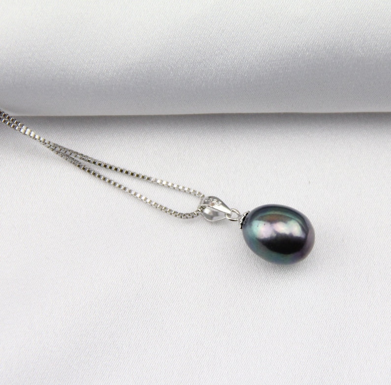 May include: A silver chain necklace with a dark gray pearl pendant.