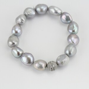 May include: A silver pearl bracelet with a silver and clear crystal bead in the center.