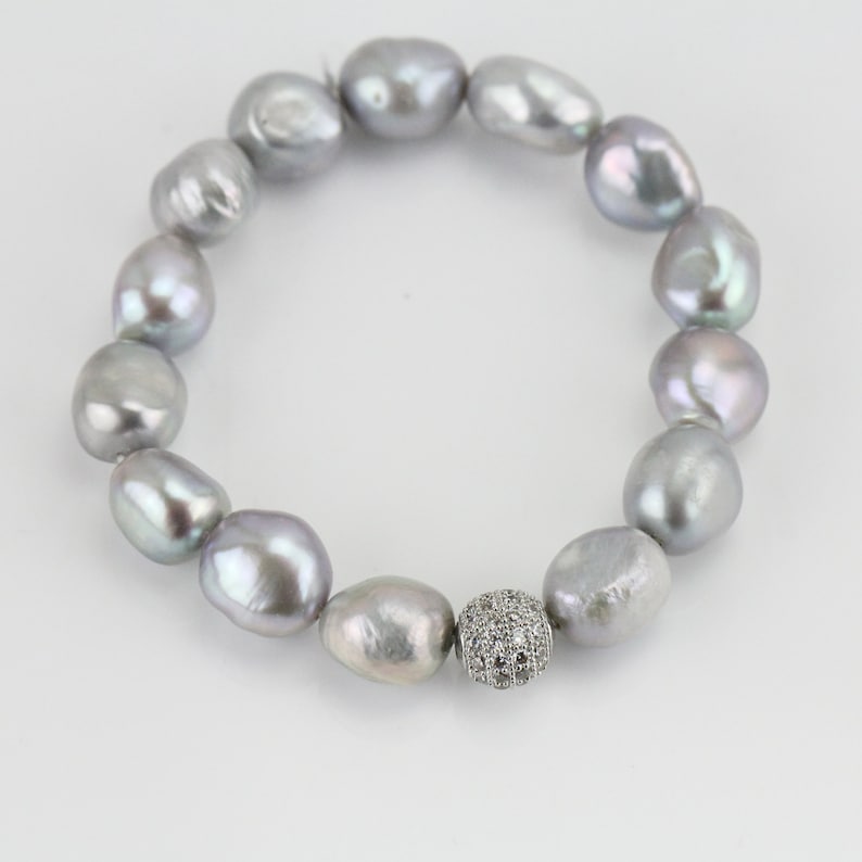 May include: A silver pearl bracelet with a silver and clear crystal bead in the center.