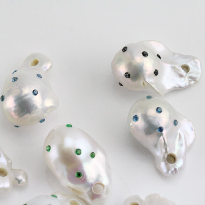 Pode incluir: Uma cole&ccedil;&atilde;o de p&eacute;rolas barrocas brancas com diferentes pedras de cristal coloridas. As p&eacute;rolas s&atilde;o de forma irregular e t&ecirc;m um furo perfurado.