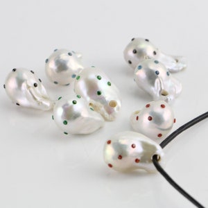 Pode incluir: Uma cole&ccedil;&atilde;o de p&eacute;rolas barrocas brancas com detalhes de pedras preciosas coloridas. As p&eacute;rolas s&atilde;o de forma irregular e t&ecirc;m um acabamento liso e brilhante. Algumas das p&eacute;rolas s&atilde;o enfiadas em um cord&atilde;o preto.