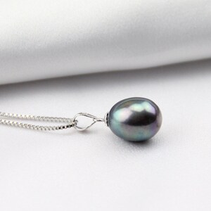 May include: A silver chain necklace with a dark green and black pearl pendant.