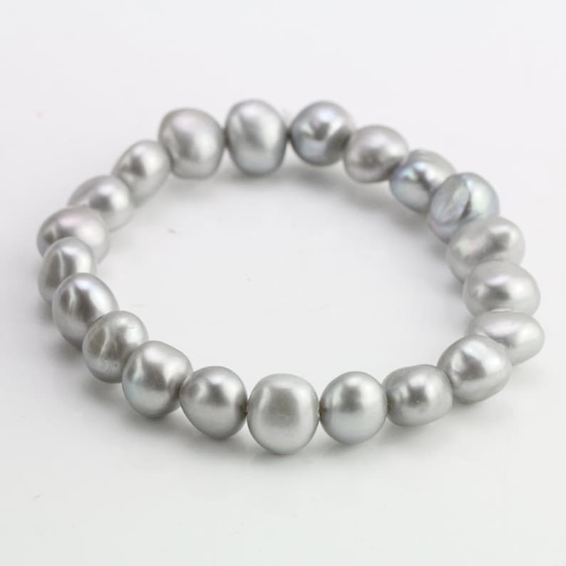 May include: A silver pearl bracelet with a simple design. The bracelet is made of a string of round, smooth pearls.