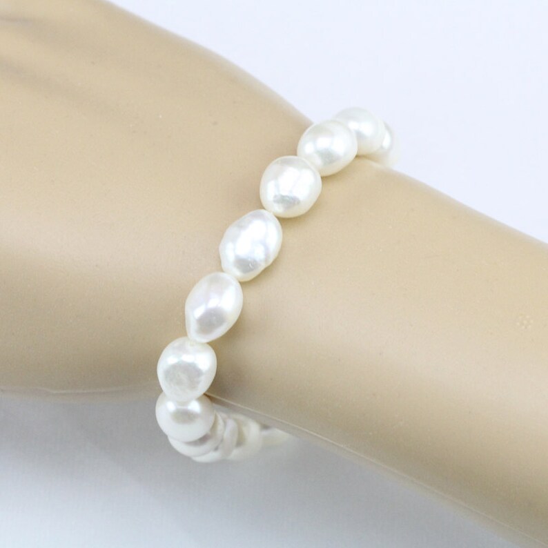 May include: A white pearl bracelet with a stretchy elastic band.