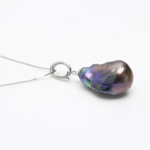 May include: A silver chain necklace with a large, iridescent black baroque pearl pendant.