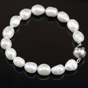 May include: A white pearl bracelet with a silver magnetic clasp. The pearls are round and smooth, and the bracelet is approximately 7 inches in length.