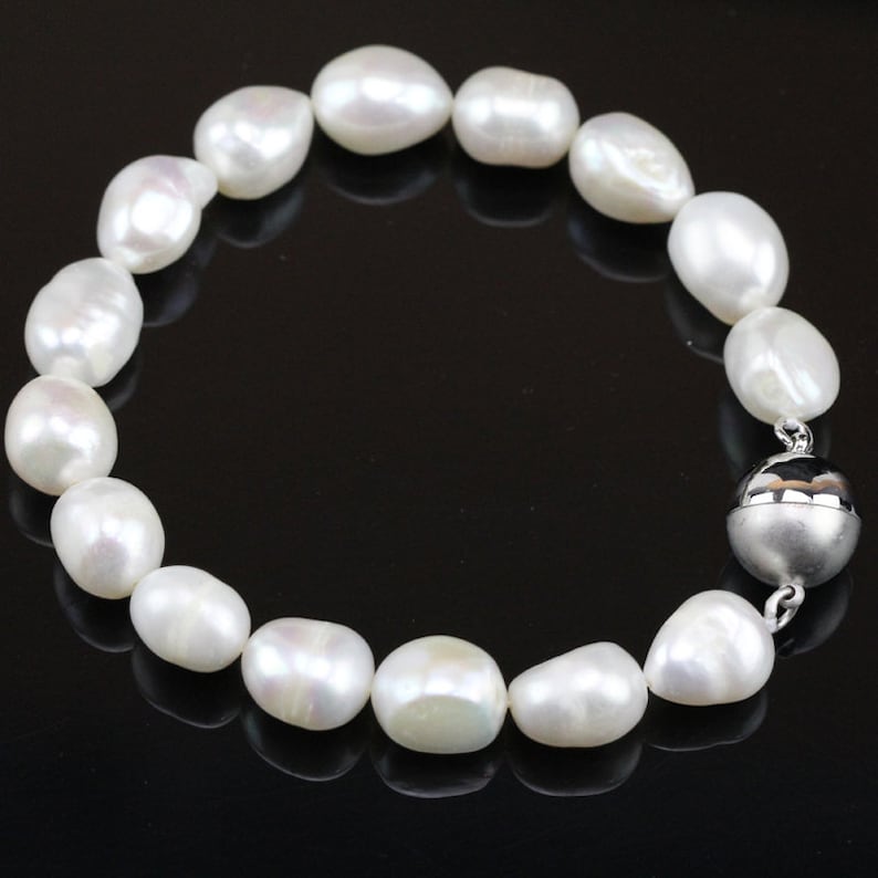 May include: A white pearl bracelet with a silver magnetic clasp. The pearls are round and smooth, and the bracelet is approximately 7 inches in length.