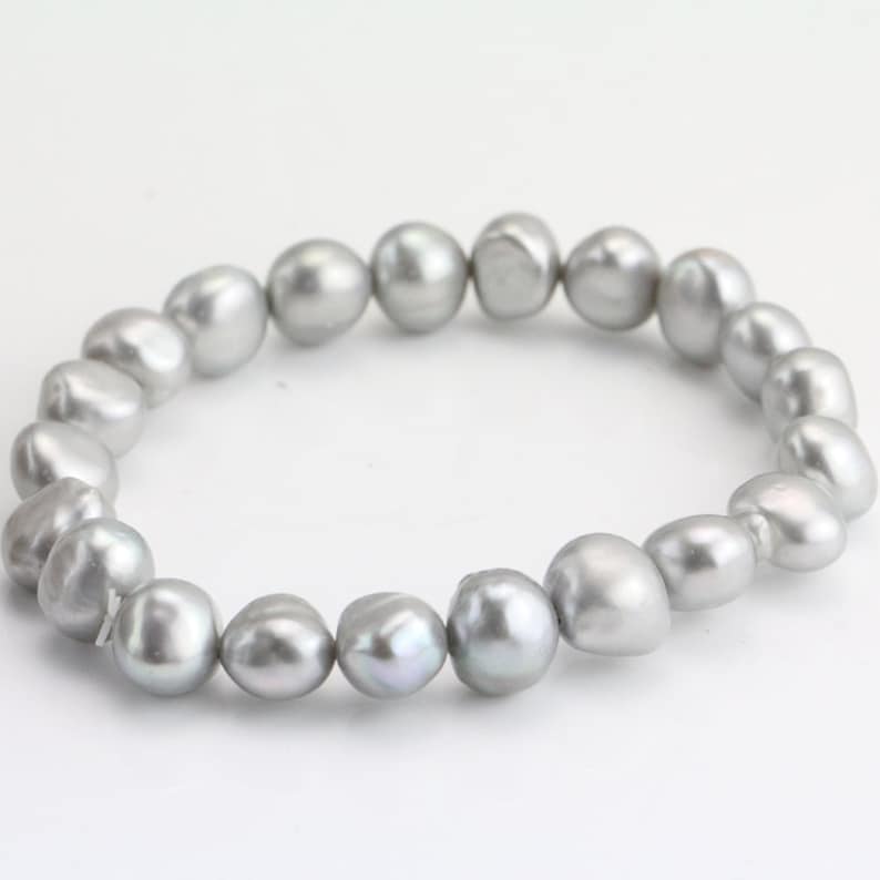 May include: A silver pearl bracelet with a simple design. The pearls are all the same size and shape, and they are strung together on a clear elastic cord.
