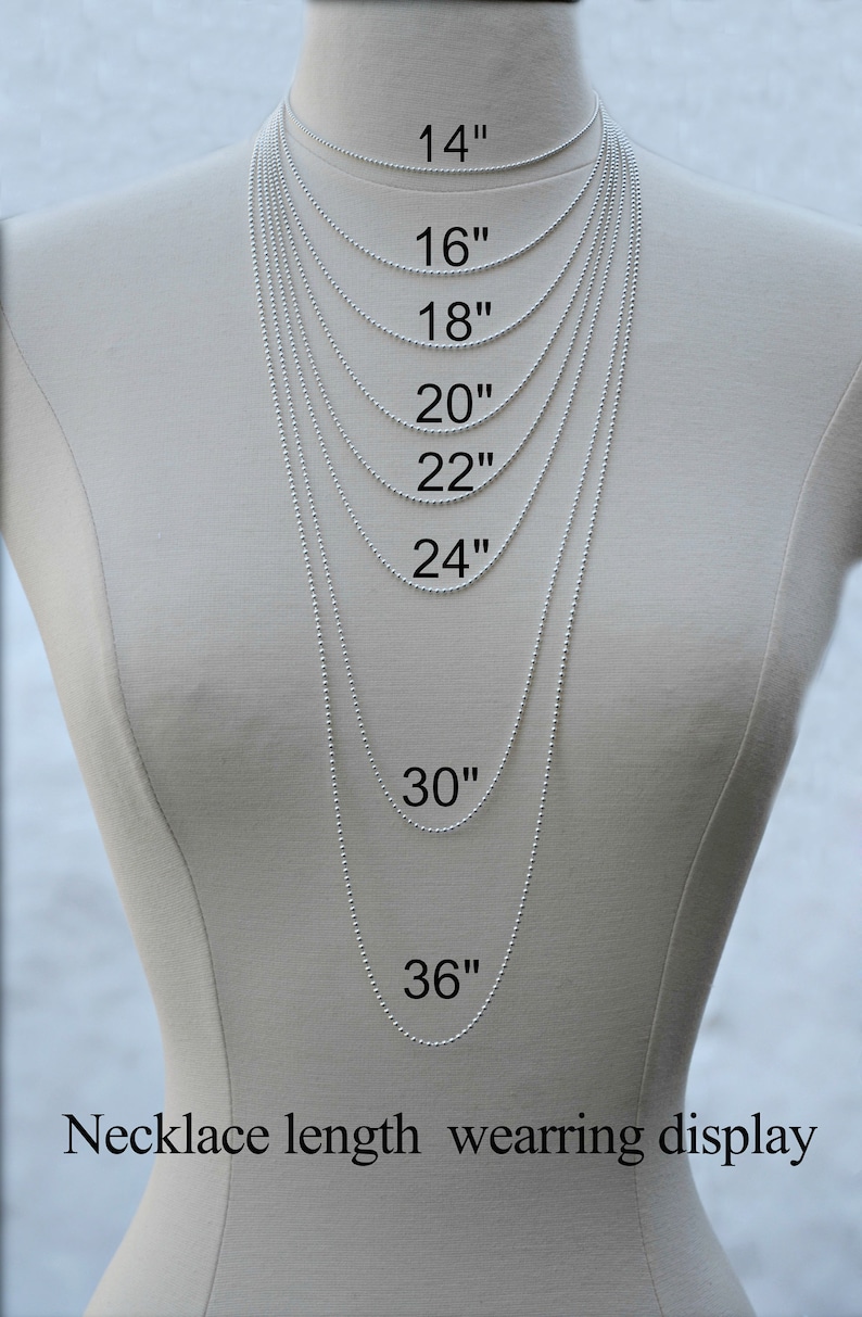 May include: A white mannequin wearing a silver chain necklace in various lengths, from 14 inches to 36 inches. The necklace lengths are labeled in inches. The image shows how different necklace lengths look when worn.