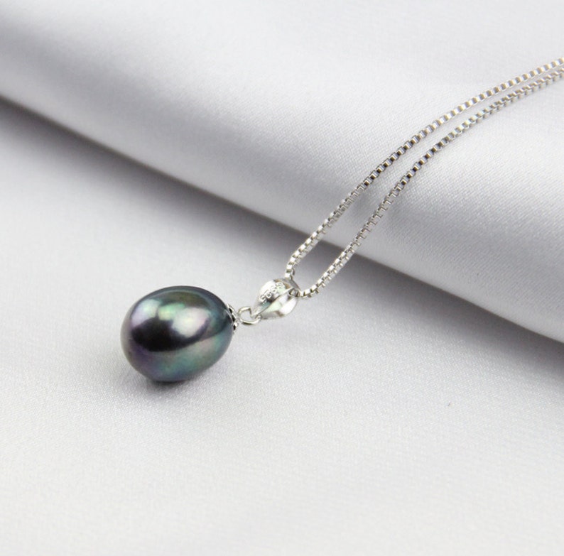 May include: A silver chain necklace with a single large black pearl pendant.