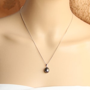 May include: A silver chain necklace with a single black pearl pendant.