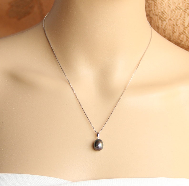 May include: A silver chain necklace with a single black pearl pendant.