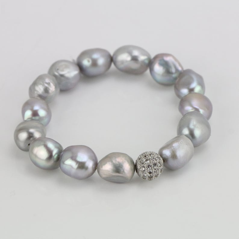 May include: A silver pearl bracelet with a silver and crystal bead in the center.