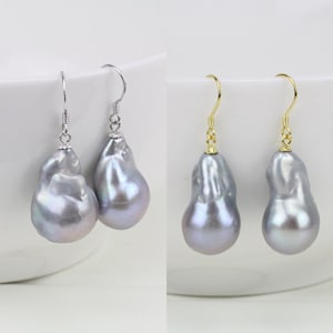 May include: A pair of silver and gold earrings with large, irregular, gray baroque pearls. The pearls have a pearlescent sheen.