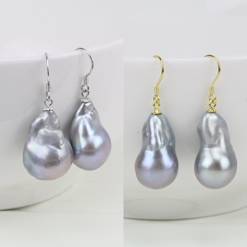 May include: A pair of silver and gold earrings with large, irregular, gray baroque pearls. The pearls have a pearlescent sheen.
