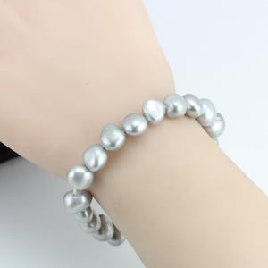 May include: A silver pearl bracelet with a simple design. The bracelet is made of a string of round, smooth pearls.