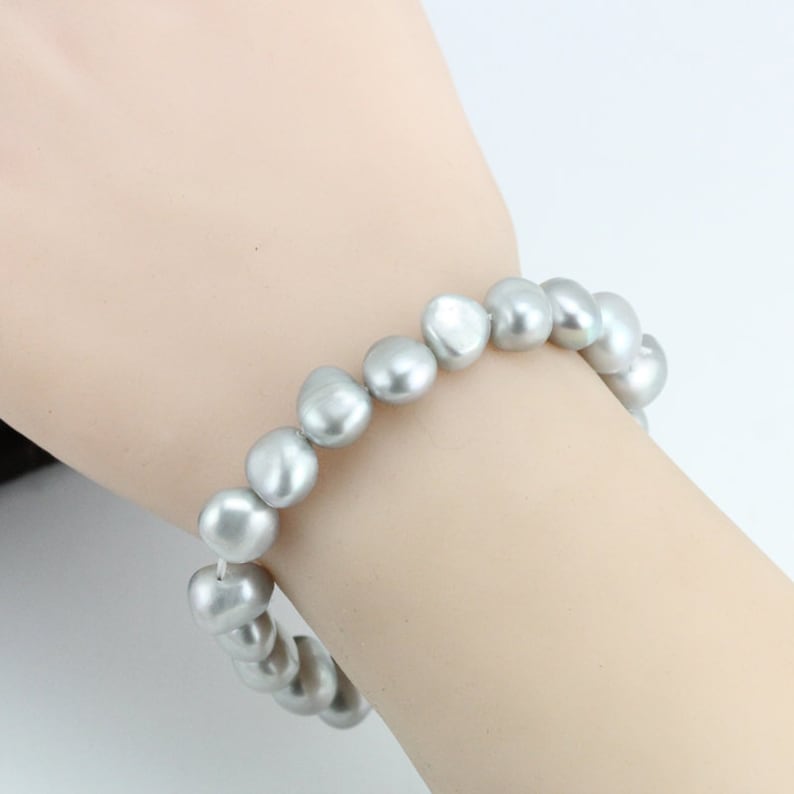 May include: A silver pearl bracelet with a simple design. The bracelet is made of a string of round, smooth pearls.