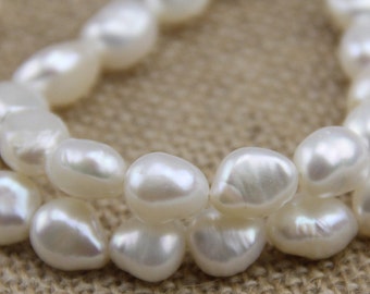 May include: A strand of white pearl beads, with a close-up view of the pearls. The pearls are smooth and round, and they are arranged in a loose, flowing pattern.