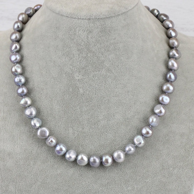 May include: A necklace of gray freshwater pearls. The pearls are irregularly shaped and strung together, creating a classic jewelry piece. The necklace is displayed on a gray mannequin bust, showcasing the necklace's length and design.