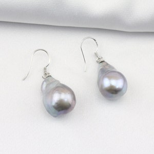 May include: A pair of silver dangle earrings with large, irregular, gray baroque pearls.