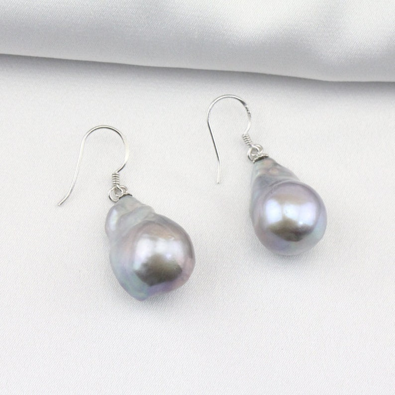 May include: A pair of silver dangle earrings with large, irregular, gray baroque pearls.