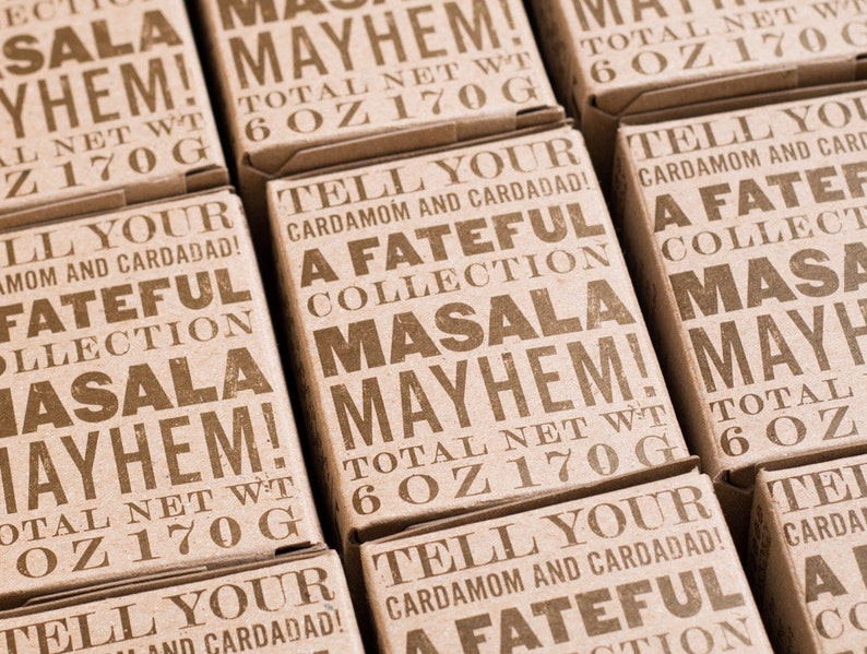 Puede incluir: Primer plano de seis cajas de cart&oacute;n marr&oacute;n con el texto "A Fateful Collection Masala Mayhem!" impreso en ellas. Cada caja tiene un peso neto total de 170 g (6 oz).