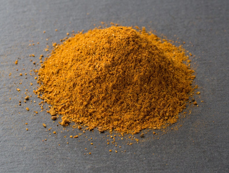 Puede incluir: Un mont&oacute;n de polvo de especias marr&oacute;n y naranja sobre una superficie gris oscura.