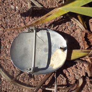 May include: Silver-toned oval belt buckle with a small sticker on the side that reads "BSX 2017". The buckle has a small inscription that reads "BC".